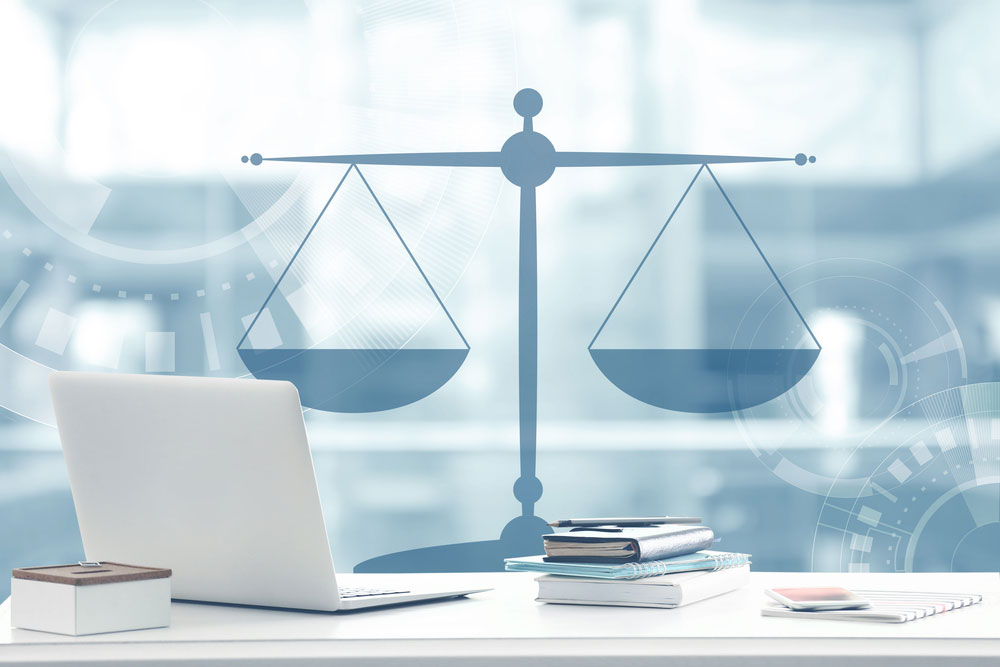 Illustration montrant un bureau avec un ordinateur et des fournitures avec en fond une balance, signe de la justice