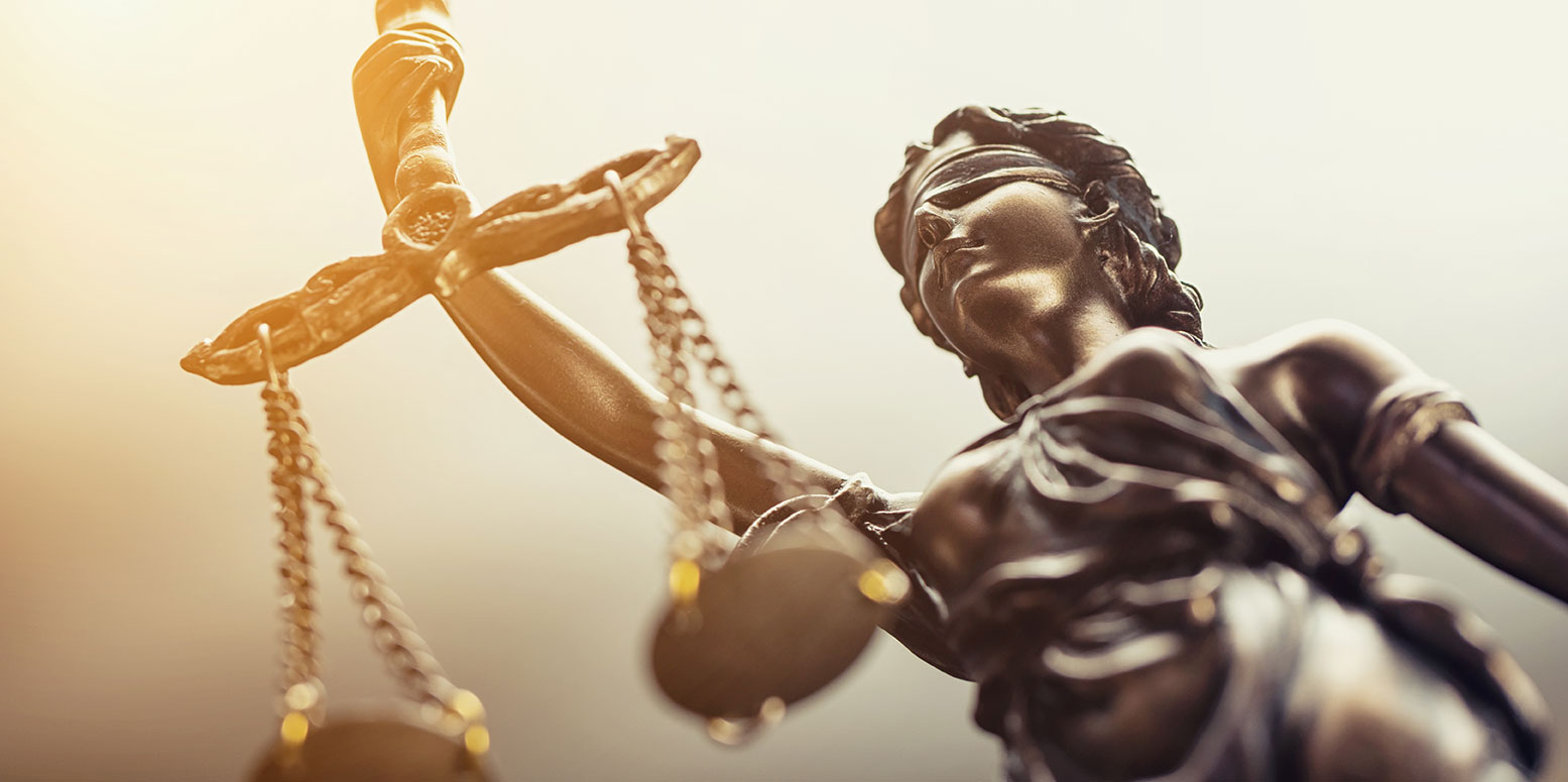 Statue d'une femme aux yeux bandés tenant une balance en hauteur, symbole de la justice