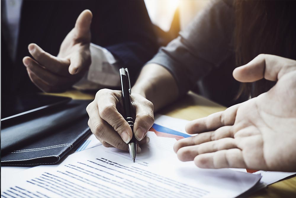 Trois personnes discutant autour d'un contrat avec un stylo prêt à le signer